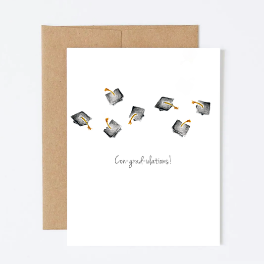 Graduation-themed card with caps and 'con grad ulations!' text, featuring a kraft envelope on a white background.