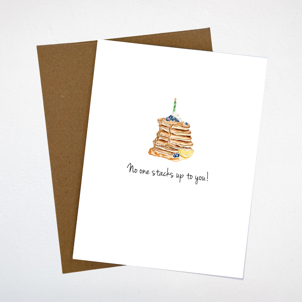 watercolor pancake stack with a birthday candle on top on a white greeting card.